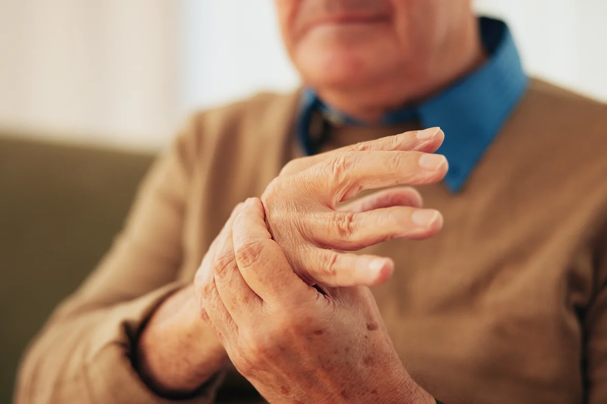 Alter Mann hält mit einer Hand seine andere Hand fest.
