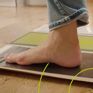 Fuß, der auf einem schwarzen Papier steht um einen Abdruck zu machen