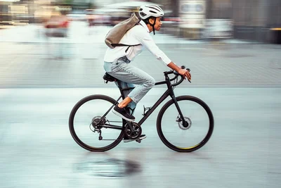 Junge Frau mit Helm auf dem Kopf fährt Fahrrad im Straßenverkehr in der Stadt.