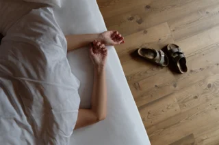 Aus einer Bettdecke ragen zwei Arme heraus