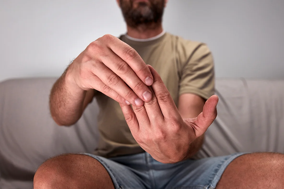 Abbildung einer Person, die auf einer Couch sitzt und sich die Finger leicht nach hinten zieht.