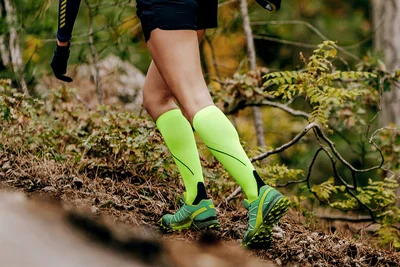 Person trägt auffällige Kompressionsstrümpfe beim Joggen im Wald
