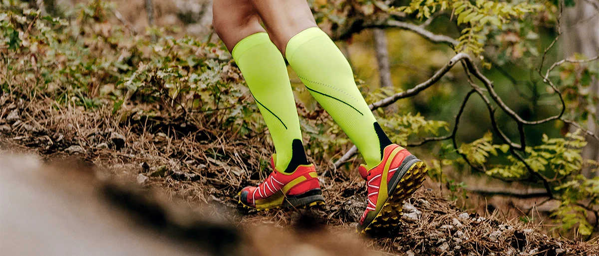 Person trägt auffällige Kompressionsstrümpfe beim Joggen im Wald