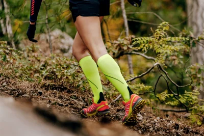 Person trägt auffällige Kompressionsstrümpfe beim Joggen im Wald