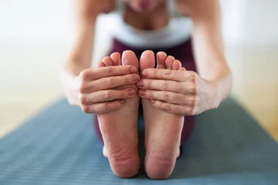 Person greift sich mit beiden Händen an die Füße