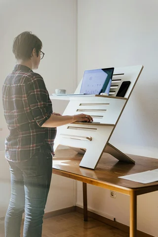 Person, die an einem Stehtisch mit dem Laptop arbeitet