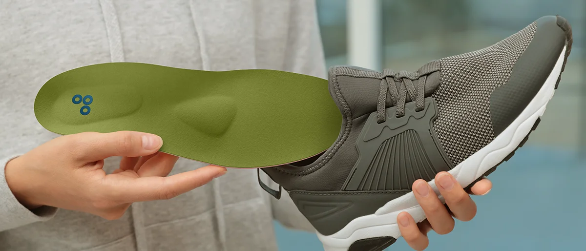 Eine Person legt eine orthopädische Einlage in einen Turnschuh