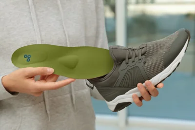 Eine Person legt eine orthopädische Einlage in einen Turnschuh