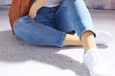 Abbildung von Beinen einer auf dem Boden sitzenden Person, die Kompressionsstrümpfe trägt