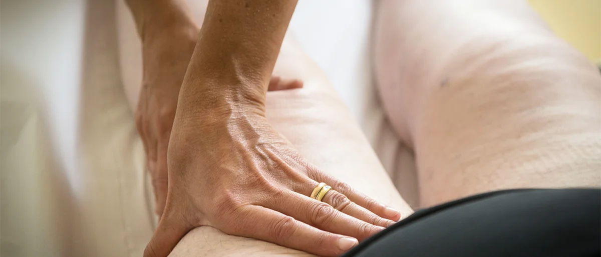 Zwei Hände massieren einen Oberschenkel