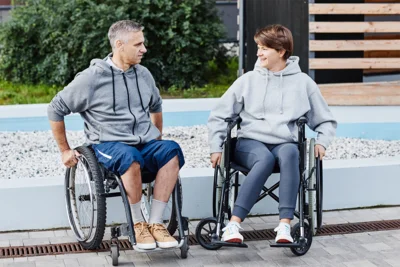 Zwei Personen sitzen im Rollstuhl und unterhalten sich miteinander