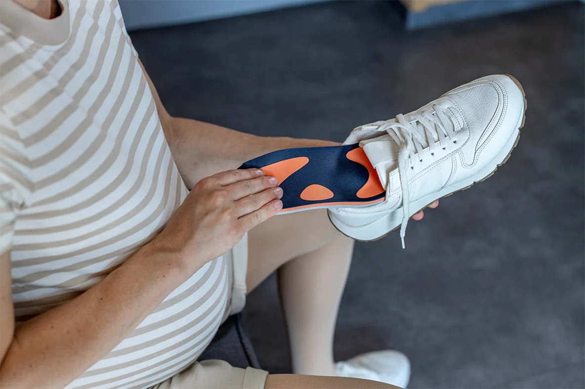 Schwangere Frau legt eine Schuheinlage von Bauerfeind in ihren Schuh